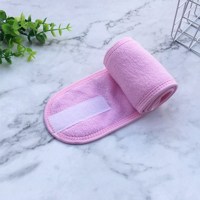 Pink soft terry cloth beauty headbands for women with velcro closure on marble surface