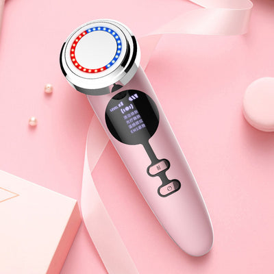 Pink electric facial cleansing brush with LED light therapy display and control buttons on a pink background