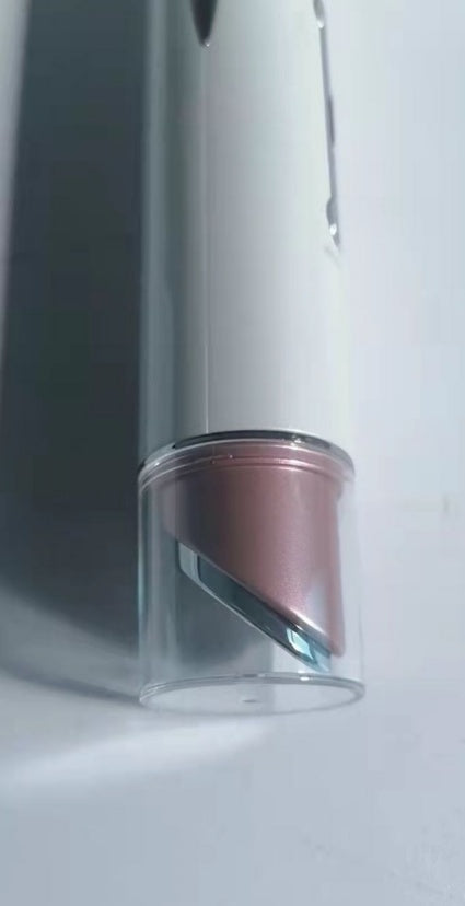 Close-up of heated eye massager with sleek white body and rose gold tip on white background