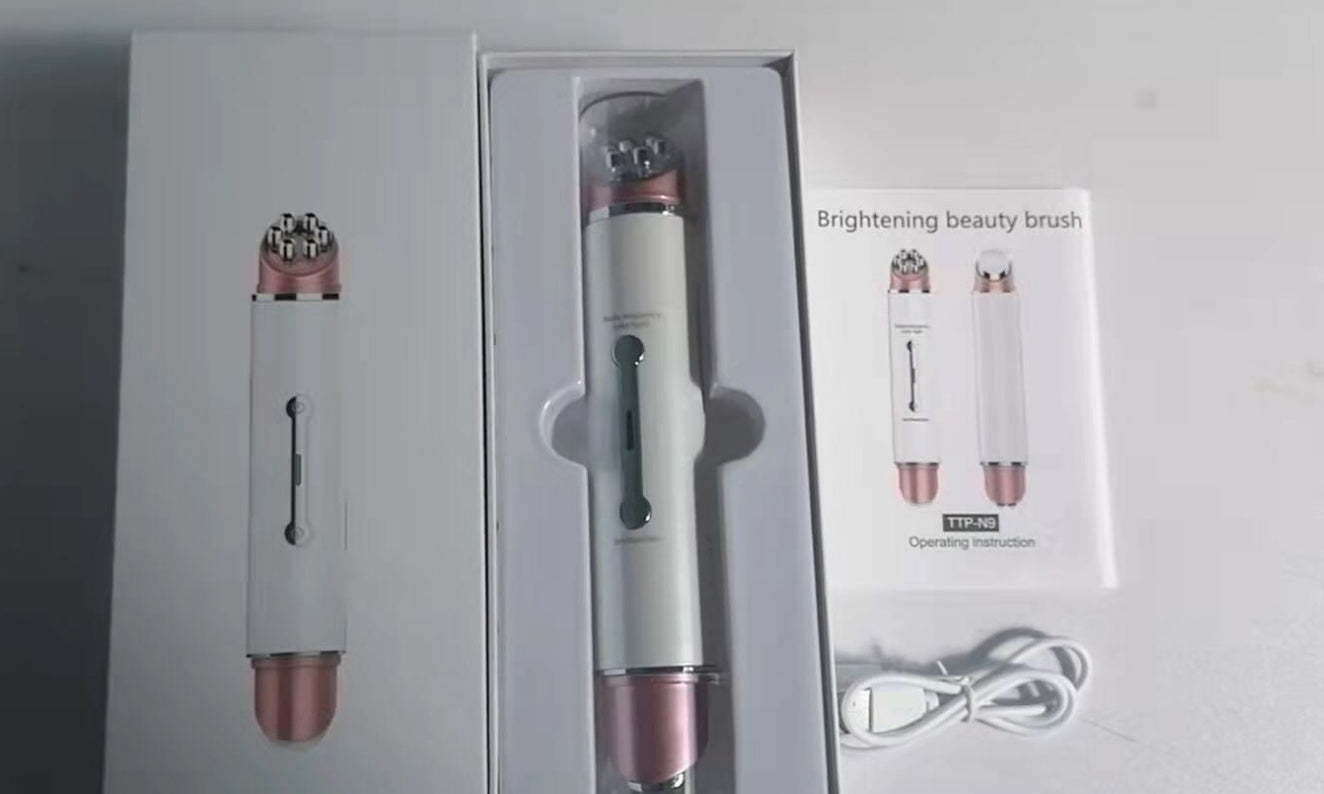 Heated eye massager with brightening beauty brush and USB charging cable in white and rose gold