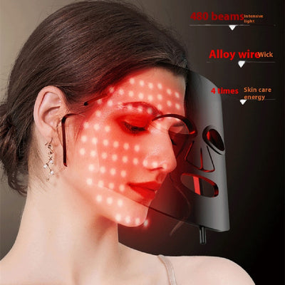 Woman wearing LED light therapy mask emitting red light beams for skin care treatment