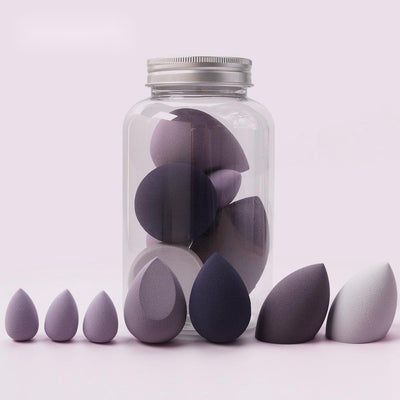 Set of purple and gray spherical makeup sponge applicators in various sizes with some inside a clear jar