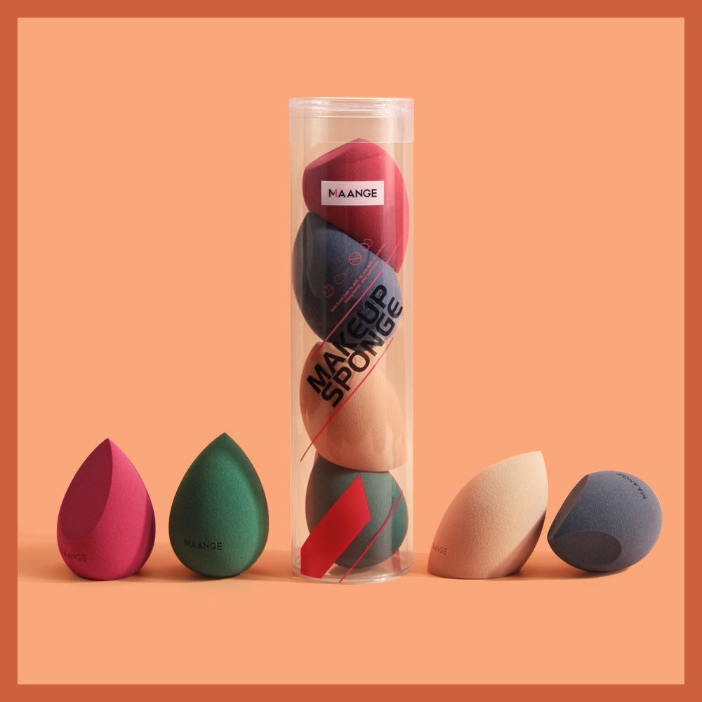 Set of colorful spherical makeup sponge in transparent packaging with additional sponges on orange background