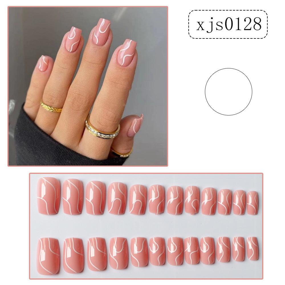 Pink press on nails for women with white abstract swirl design displayed on hand and in set